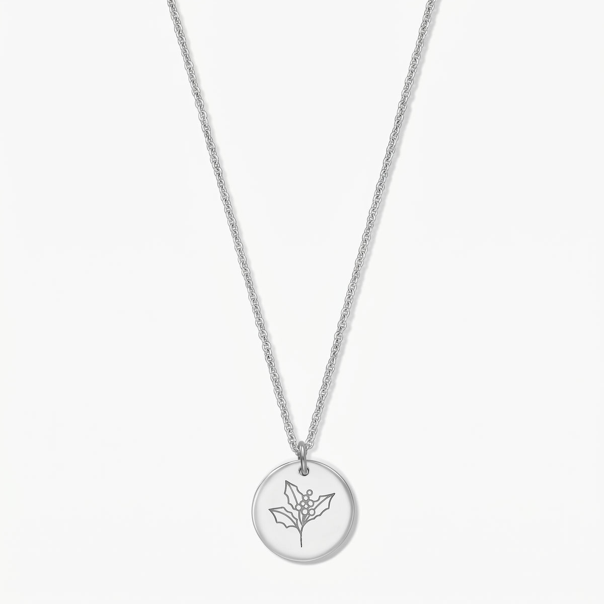 Elegant sterling silver birthflower necklace with a round pendant engraved with a holly sprig on a white background.