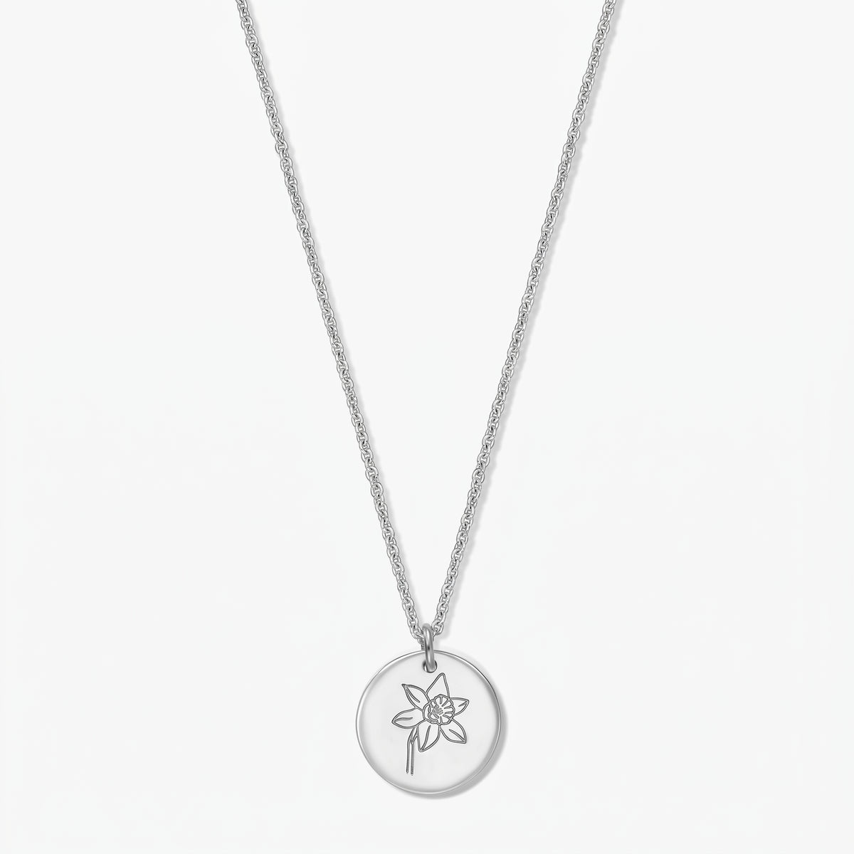 Sterling silver necklace featuring a round pendant engraved with a daffodil—the March birth flower—on a white background.