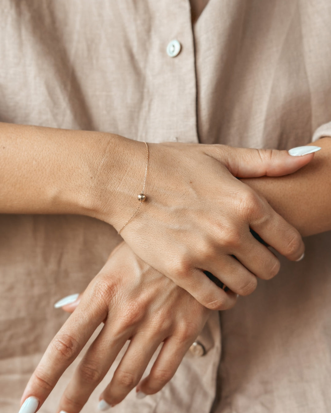 Close-up of a person's hands wearing an elegant gold bracelet.
