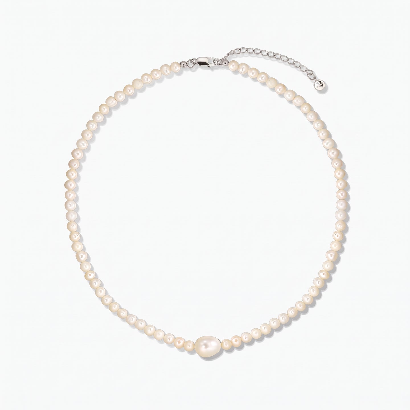 Cultured pearl necklace featuring a larger central pearl and a silver clasp with extender, photographed on a white background.