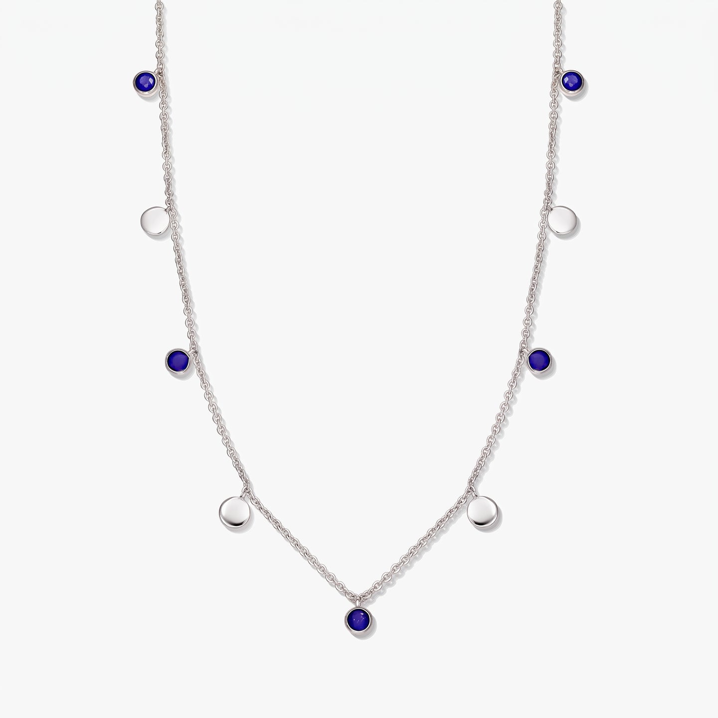 Sterling silver station necklace with round lapis lazuli cabochons and polished silver discs on a white background.