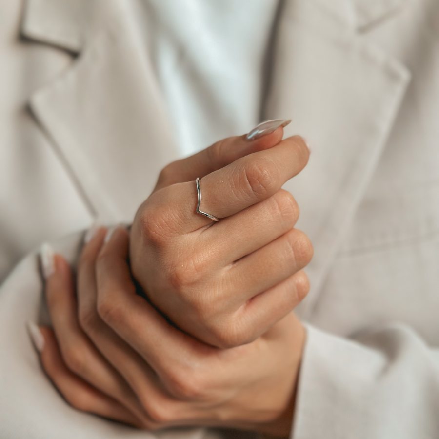 Close-up of a hand adorned with a minimalist silver V-shaped ring.