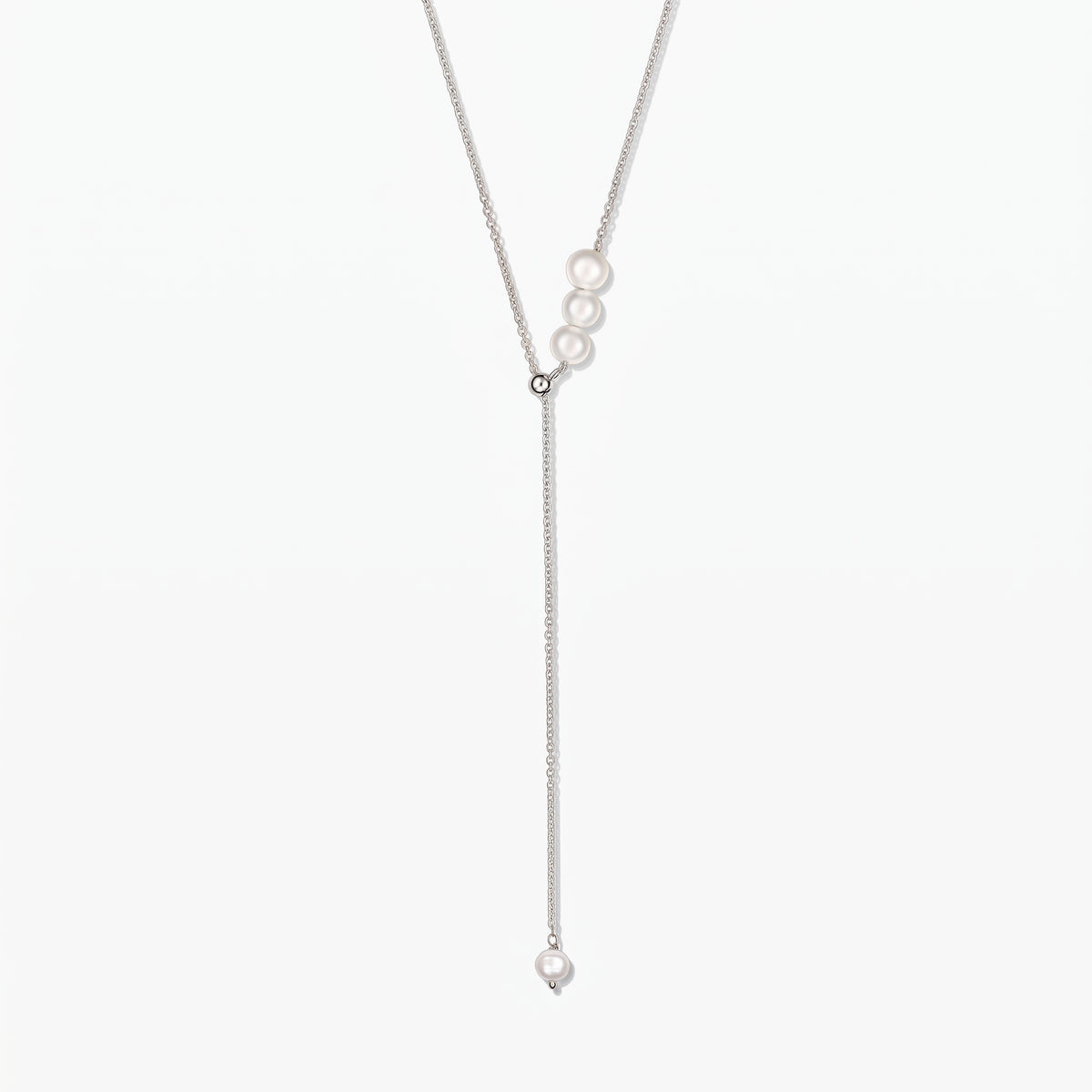 Elegant adjustable sterling silver lariat necklace with white cultured pearls, against a white background.