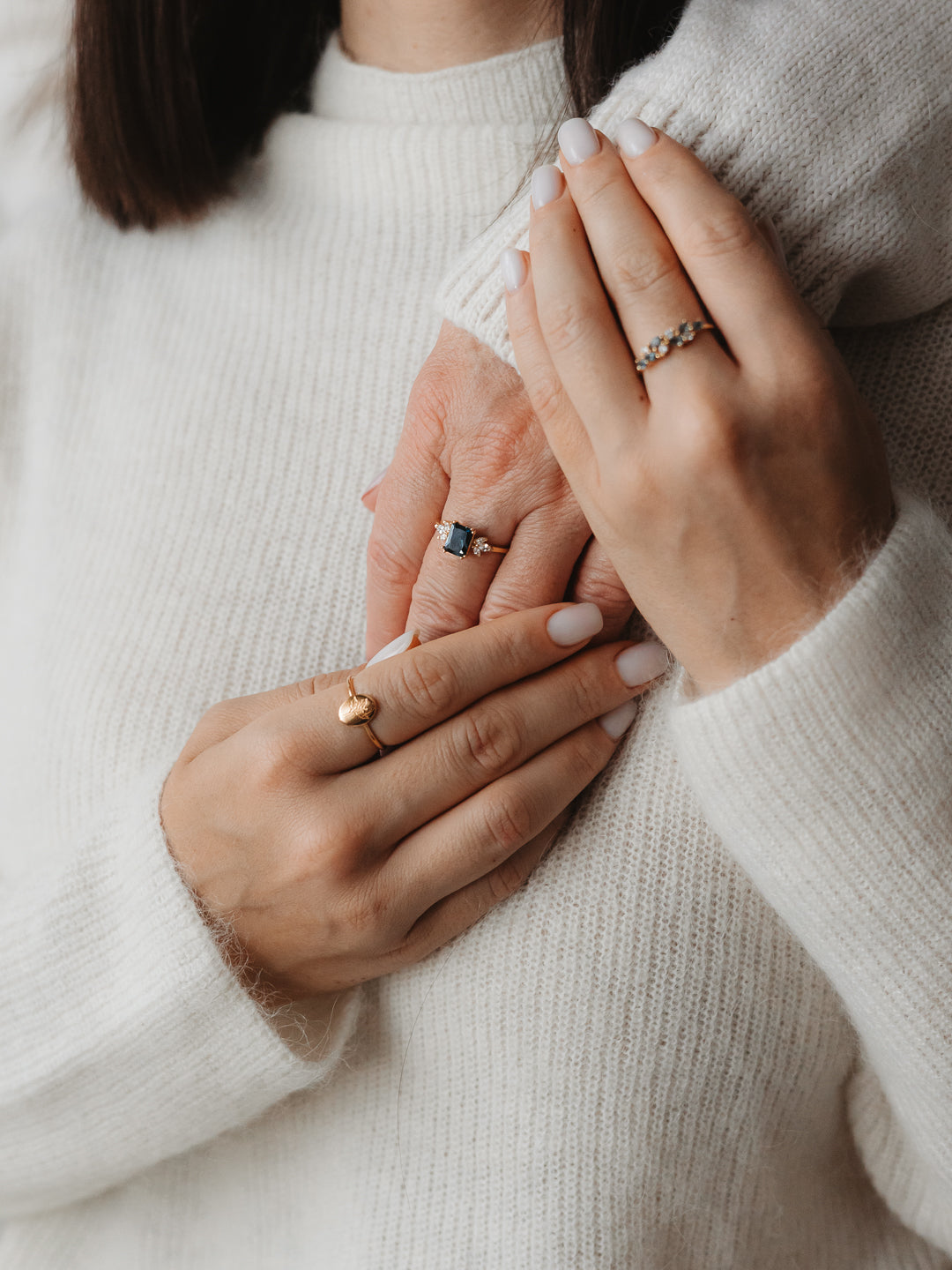 Close-up of hands showcasing elegant rings with blue topaz and gold details.