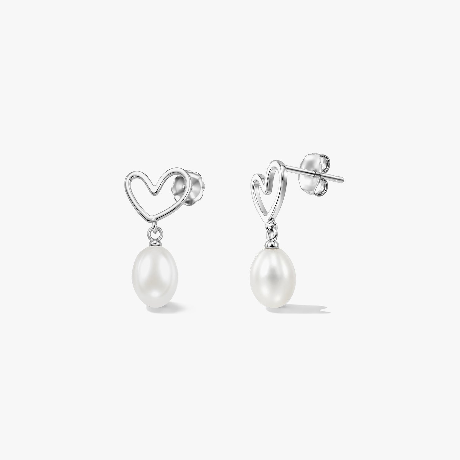 Pair of sterling silver heart stud earrings with dangling natural white pearls on a white background.