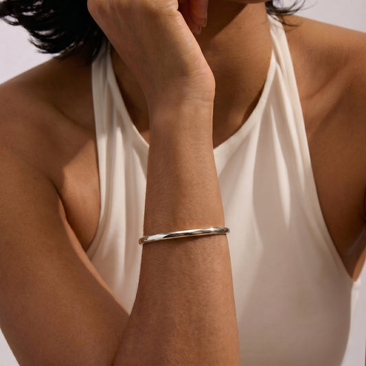A close-up of a person wearing a Serena Silver Bracelet on their arm against a plain background.