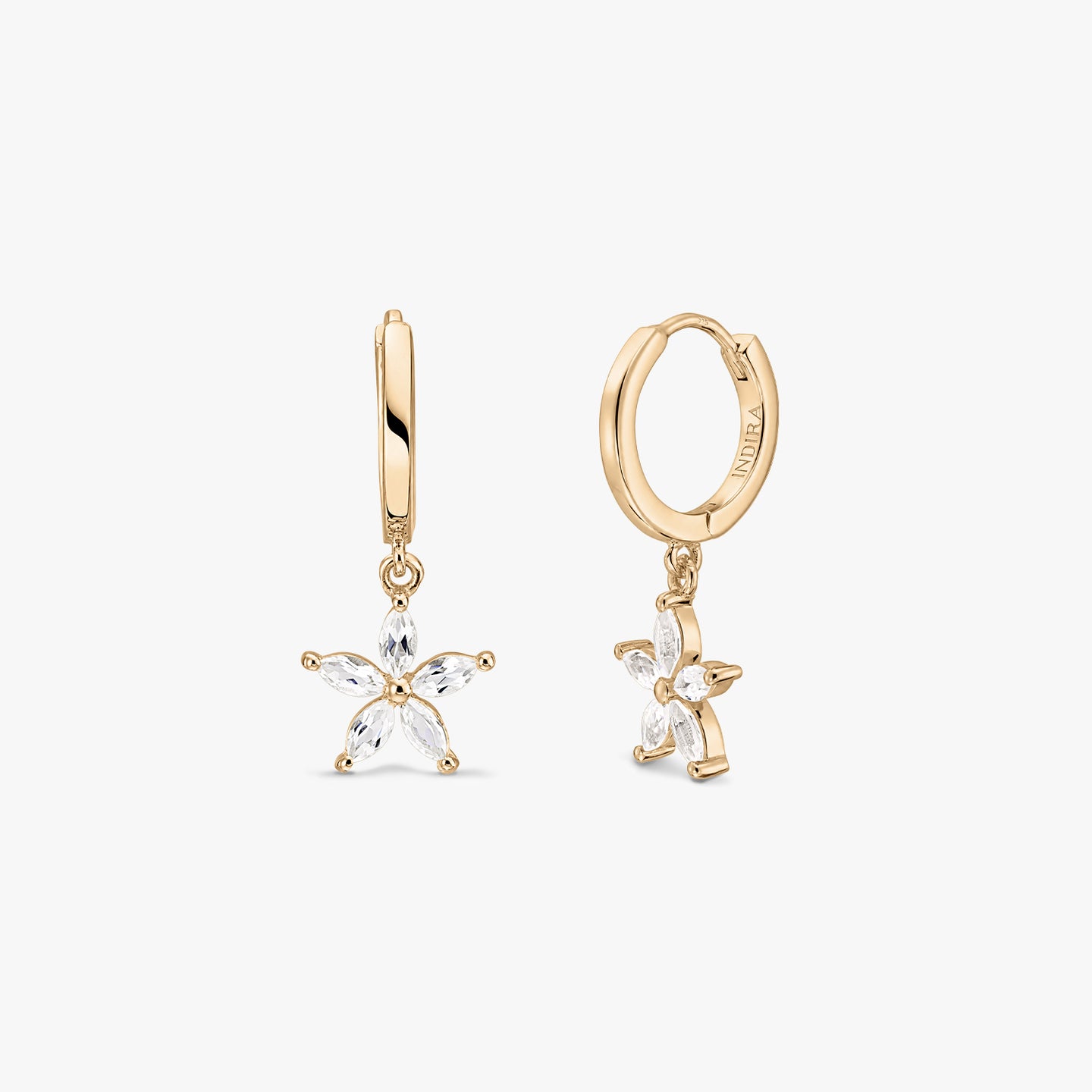 Gold-plated sterling silver huggie hoop earrings with white topaz flower charms on a white background.