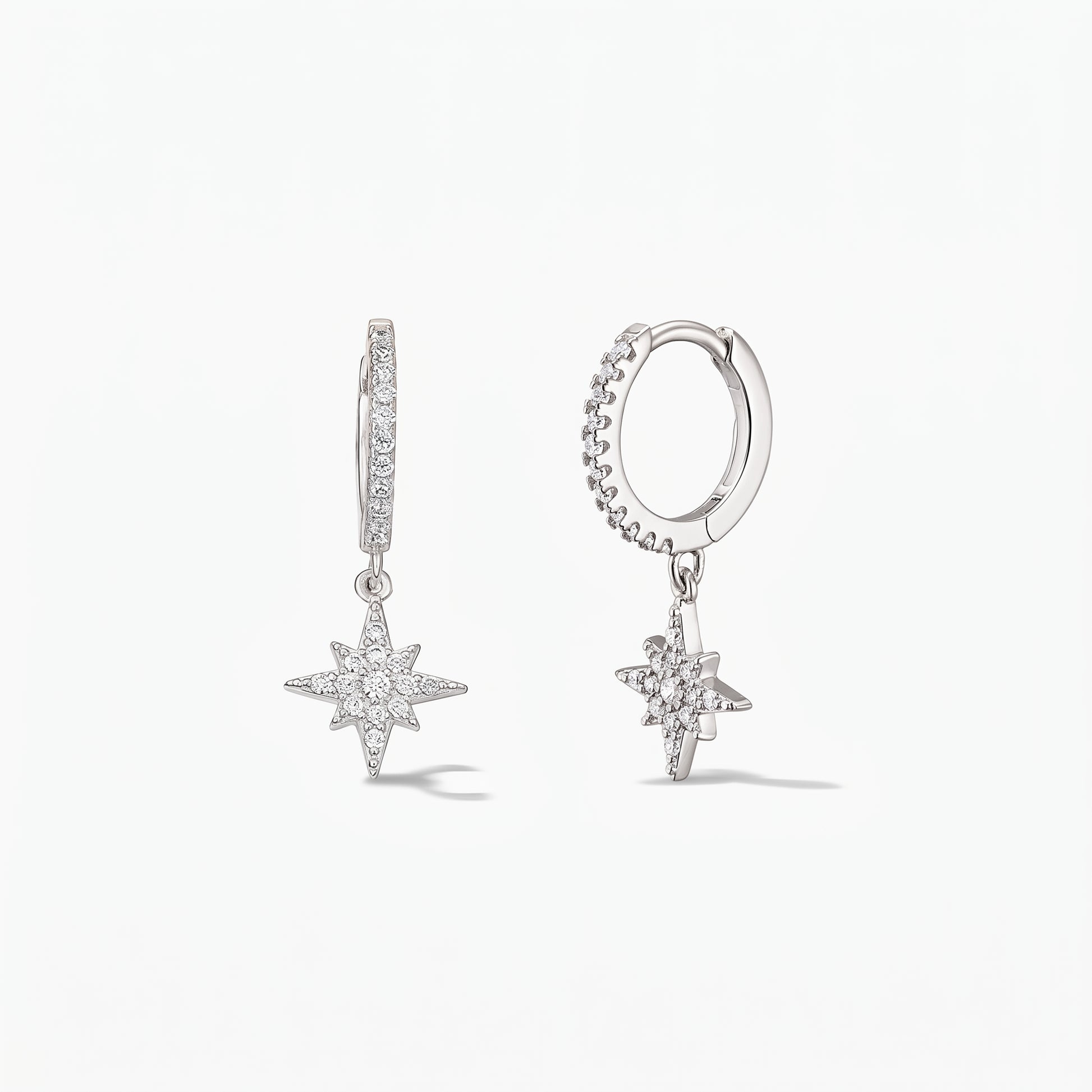 Pair of 925 sterling silver huggie hoop earrings with pavé white zirconia North Star charms on a white background.