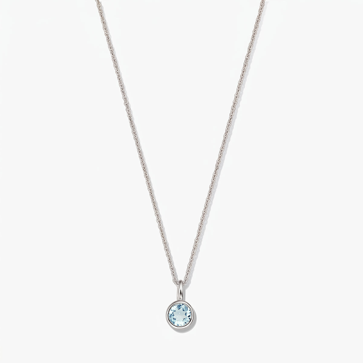 Sterling silver birthstone necklace with a small round bezel-set blue topaz pendant on a white background.
