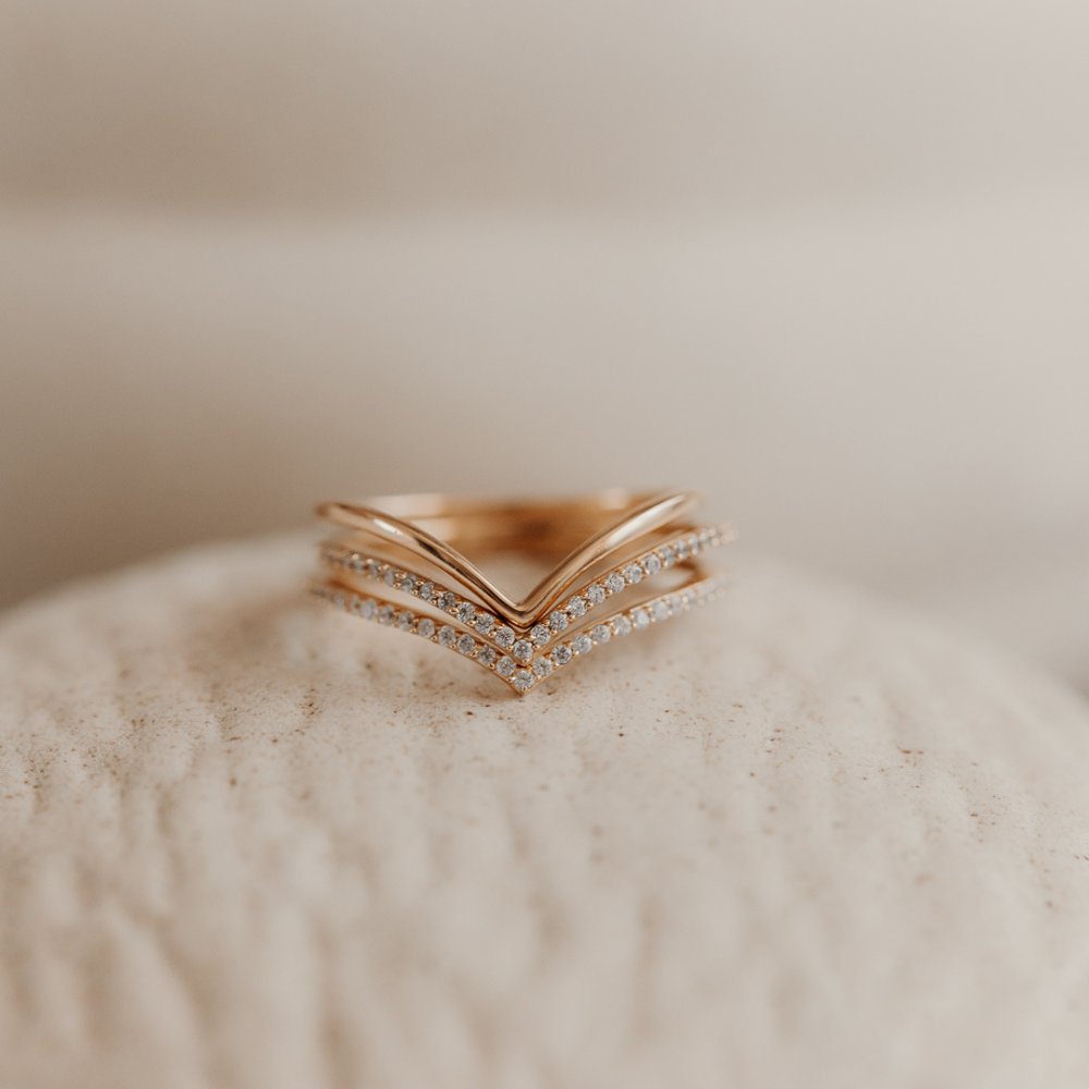 Minimalist gold-plated silver ring featuring a layered design on a textured surface.