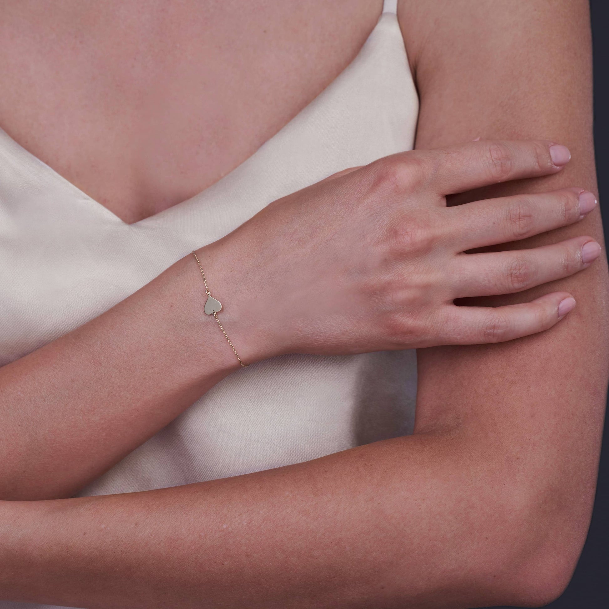Close-up of a wrist adorned with a minimalist 14K gold heart bracelet.