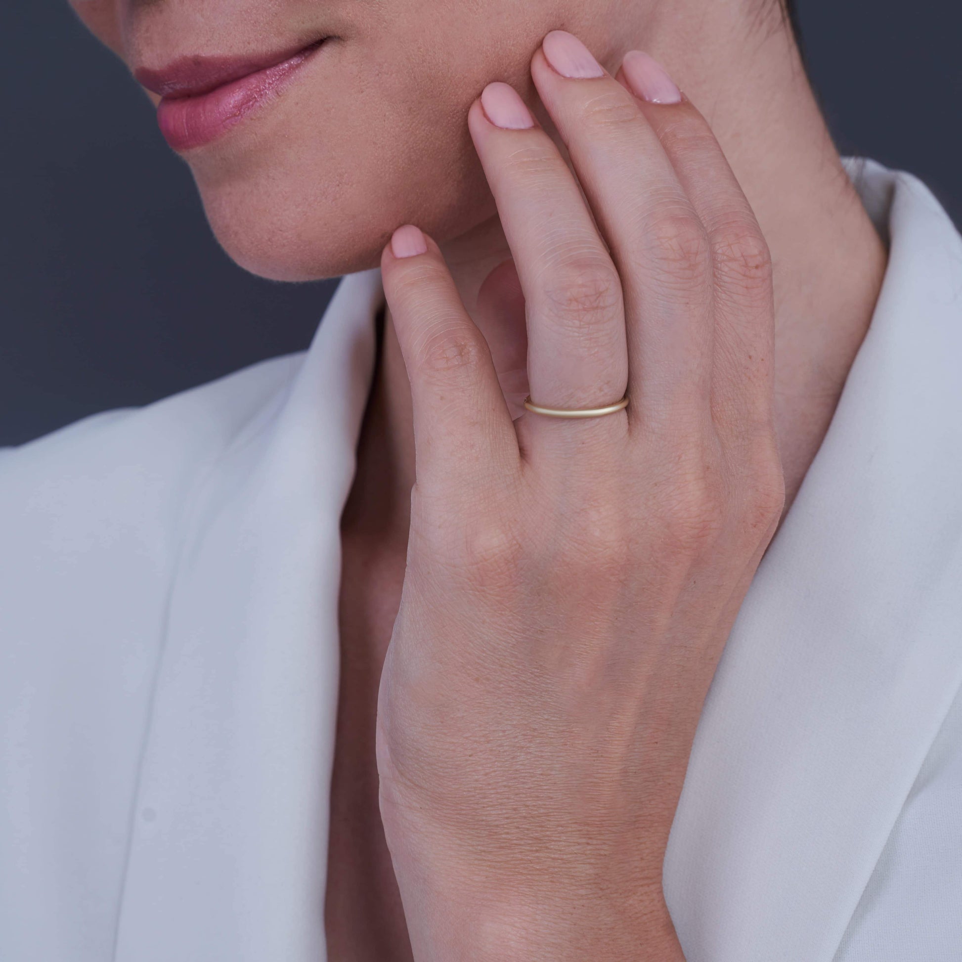A woman's hand resting on her chin, wearing a Layla Gold-Plated Silver Ring on her middle finger, with a gentle smile.