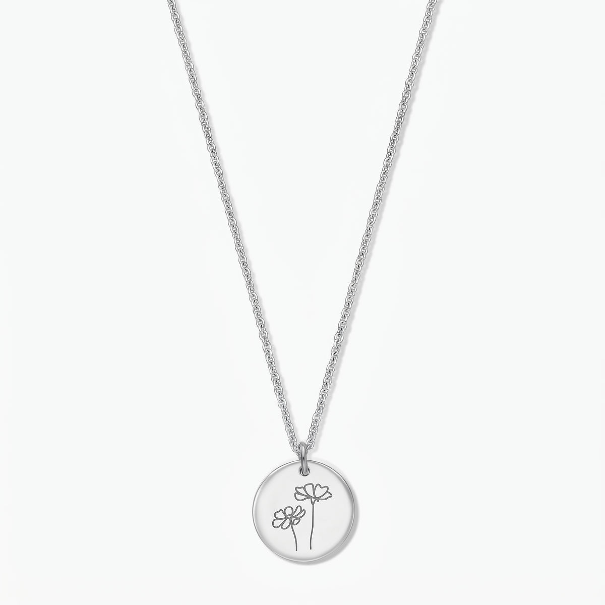 Indira sterling silver October birthflower necklace (Cosmos), featuring a round disc pendant engraved with two cosmos flowers on a delicate silver chain, isolated on a white background.