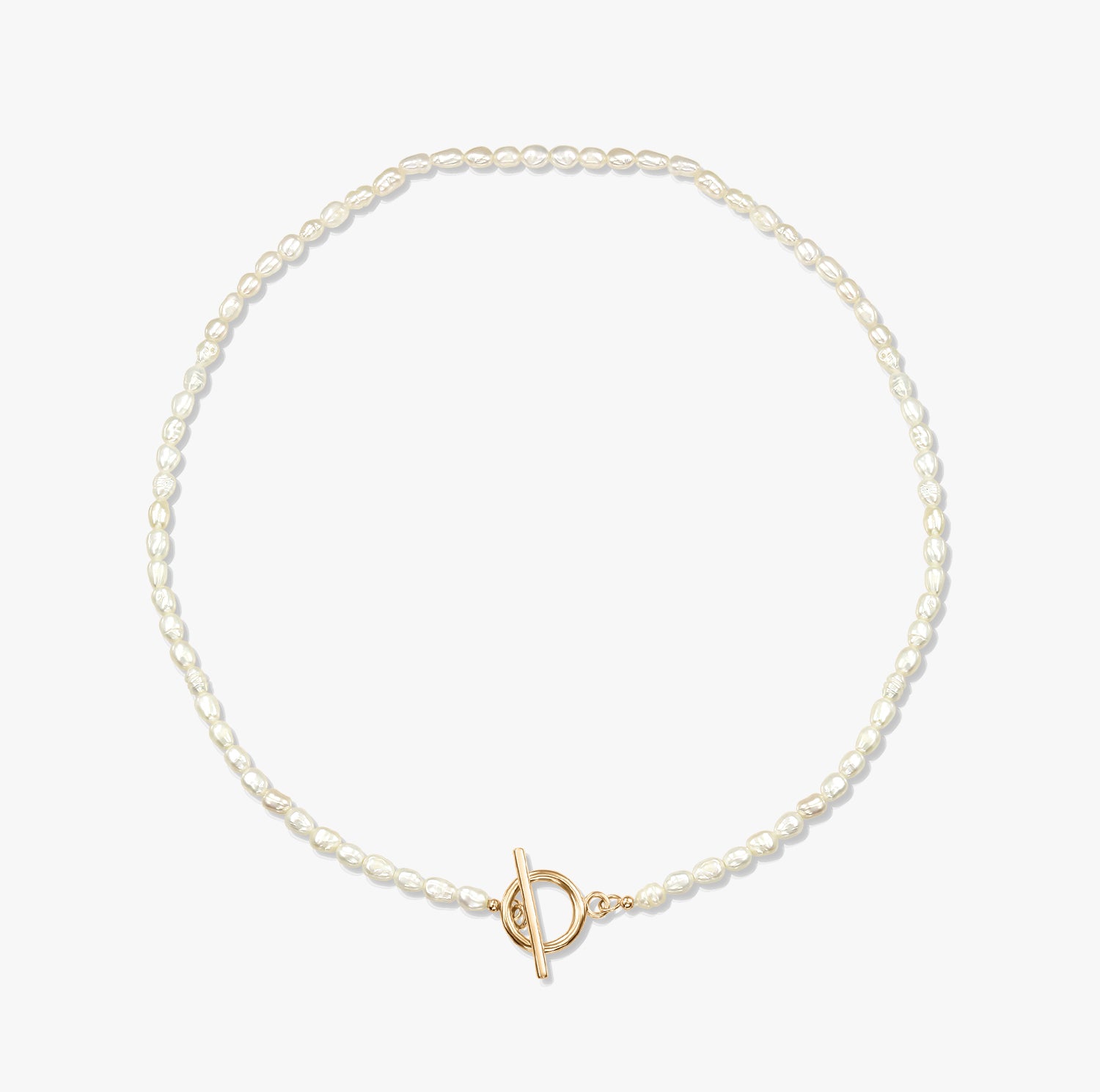 A minimalist pearl necklace with a gold toggle clasp on a white background.