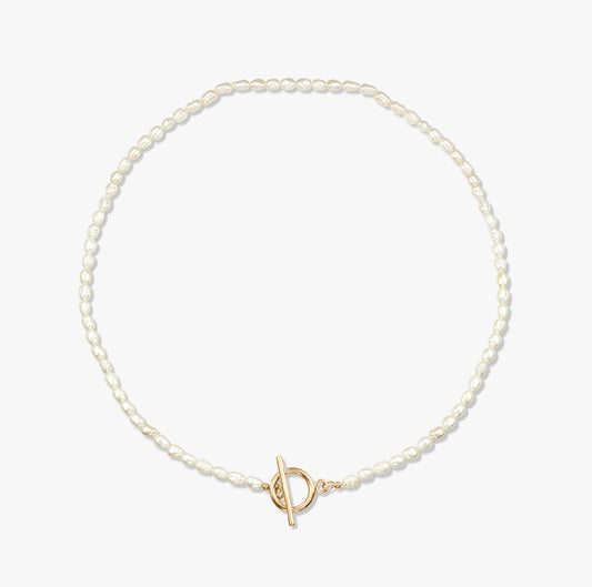A minimalist pearl necklace with a gold toggle clasp on a white background.