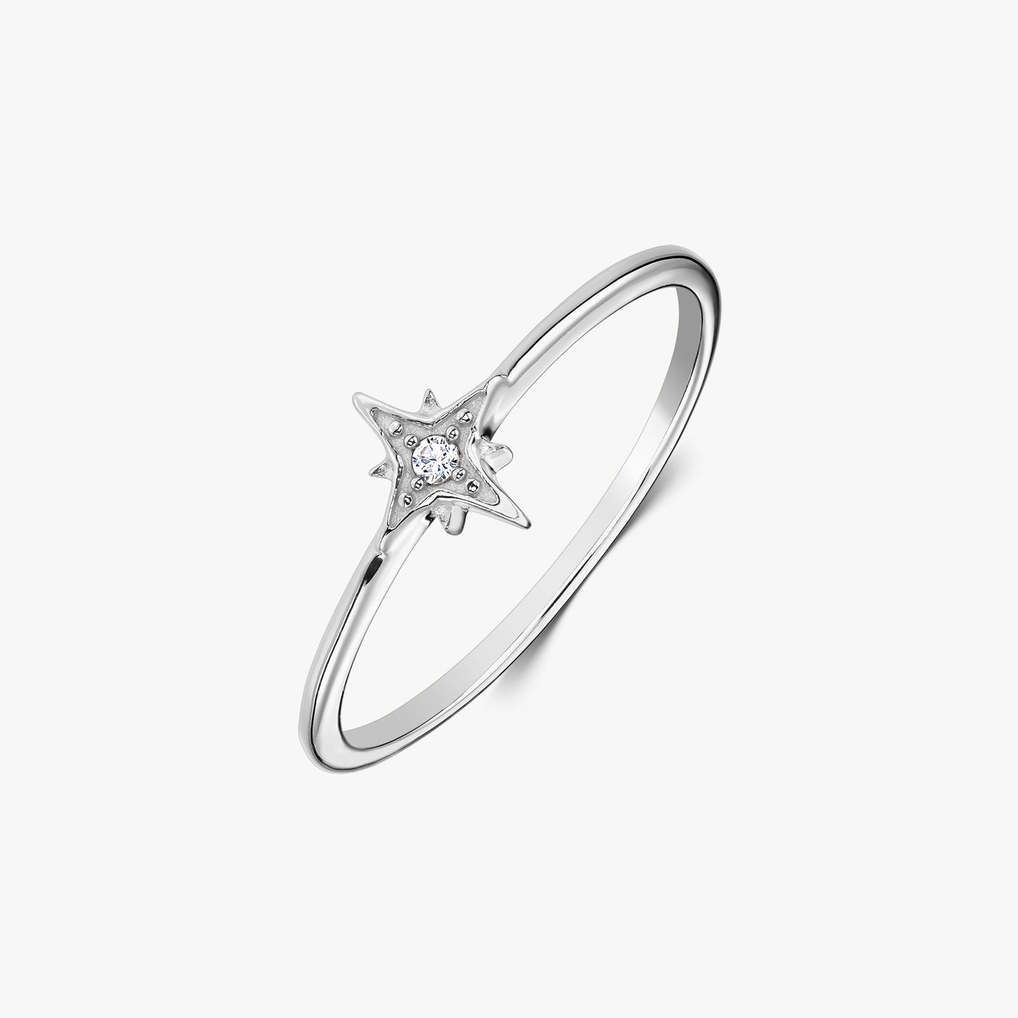 Dainty sterling silver ring with a star-shaped setting holding a white zirconia stone, photographed on a white background.