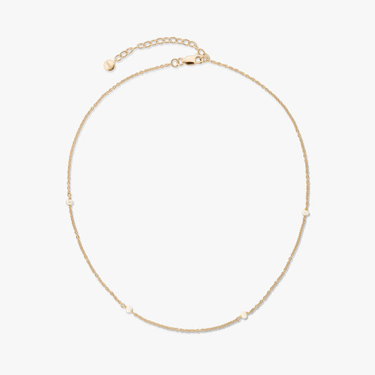Delicate gold-plated 925 silver necklace with tiny natural pearls and an adjustable extender with a lobster clasp on a white background.