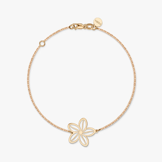 A minimalist gold bracelet with a delicate flower charm on a solid white background.