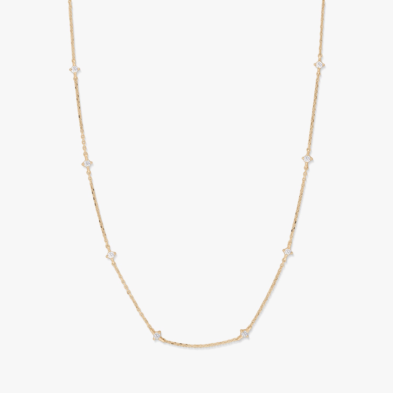 Delicate 14K yellow gold station necklace featuring small starburst-shaped white zirconia accents spaced along a fine chain, photographed on a white background.