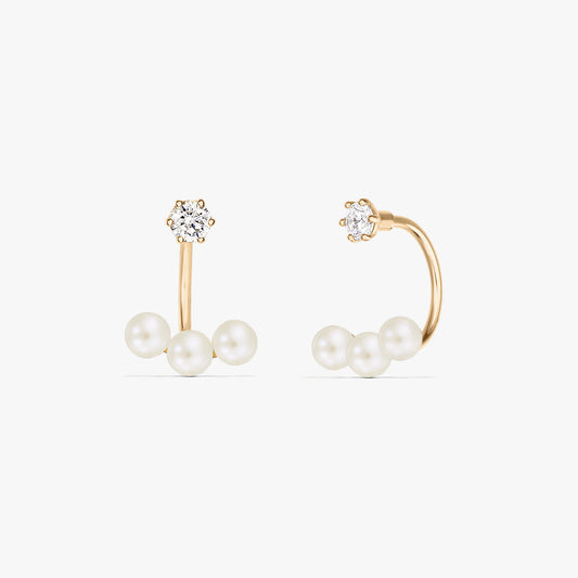 Square product photo of a pair of 14K yellow gold ear jacket earrings featuring three natural pearls beneath a small round stud on a pure white background.