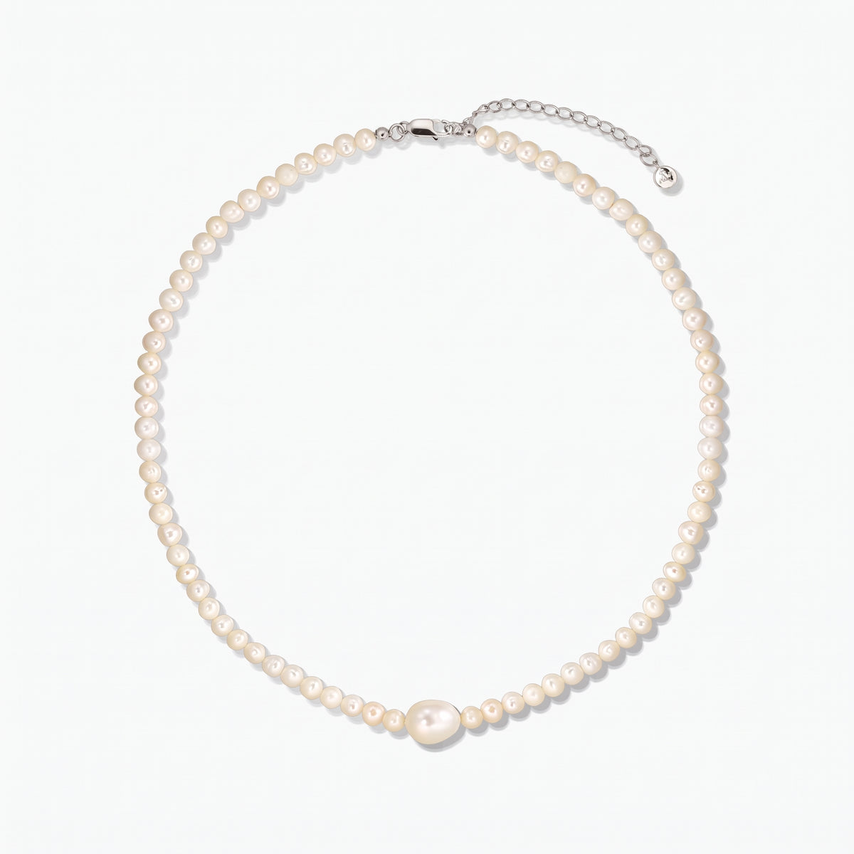 Cultured pearl necklace featuring a larger central pearl and a silver clasp with extender, photographed on a white background.