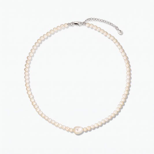 Cultured pearl necklace featuring a larger central pearl and a silver clasp with extender, photographed on a white background.