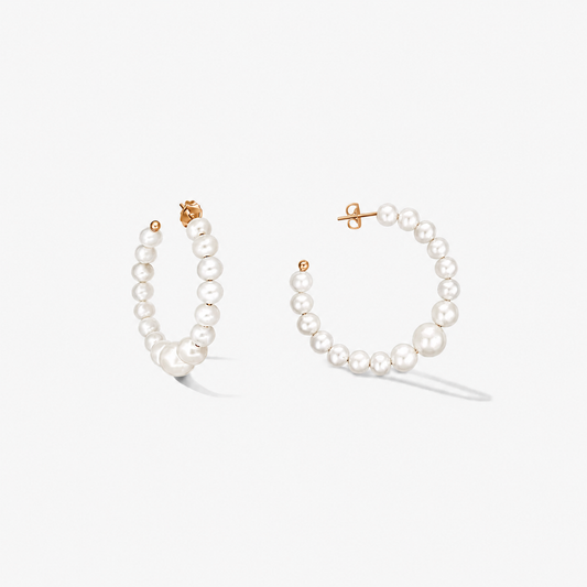Pair of gold‑plated sterling silver hoop earrings strung with graduated natural white pearls on a white background.