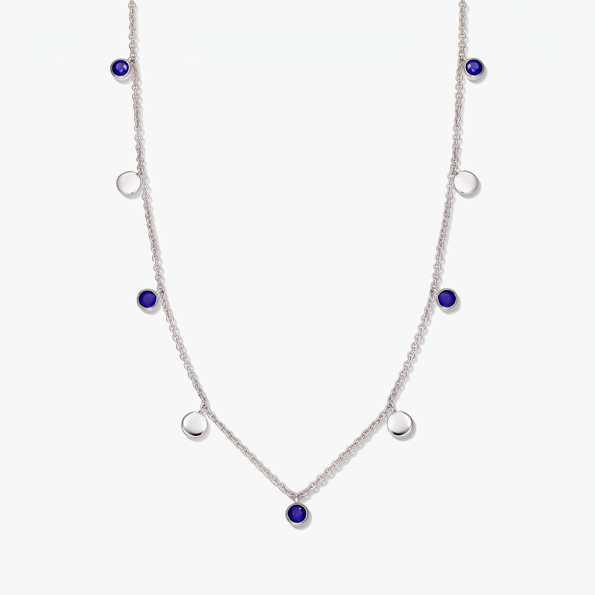 Sterling silver station necklace with round lapis lazuli cabochons and polished silver discs on a white background.