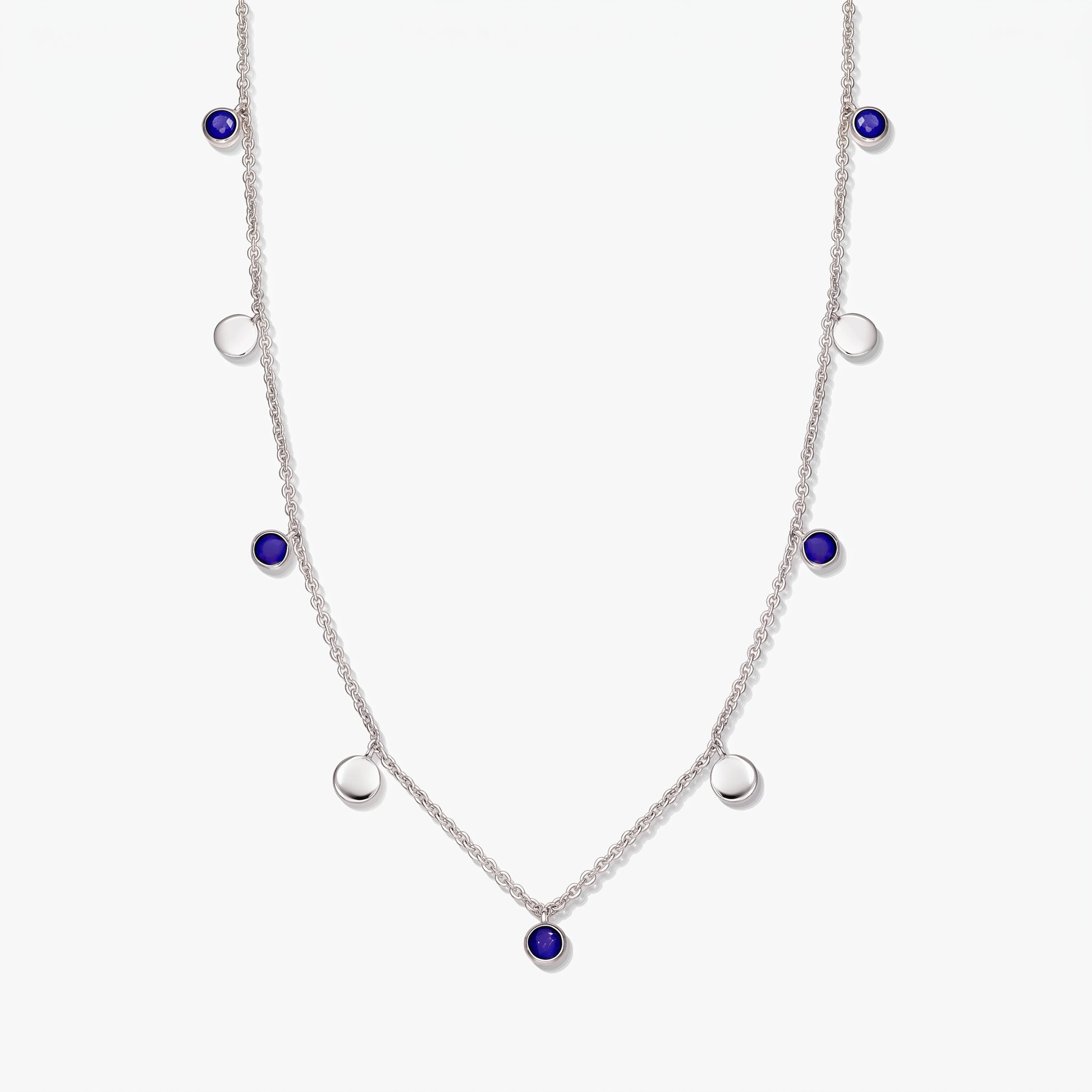 Sterling silver station necklace with round lapis lazuli cabochons and polished silver discs on a white background.