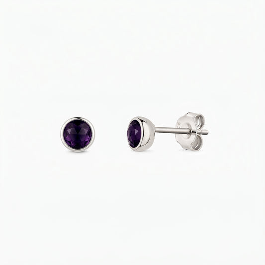 Pair of sterling silver stud earrings featuring round, faceted amethyst stones in bezel settings, shown from the front and side on a white background.