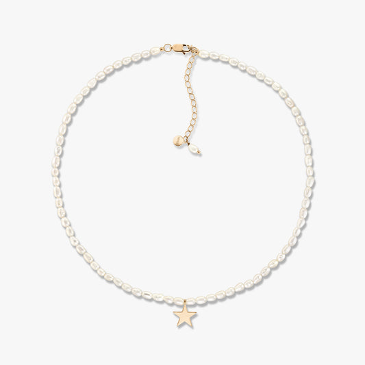 Delicate cultured pearl necklace with small gold star pendant and adjustable gold extender, displayed on a white background.