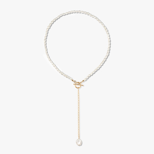 Golden Jacqueline 14K gold-plated sterling silver pearl necklace featuring a front toggle clasp and a gold drop chain ending with a single pearl, displayed on a white background.