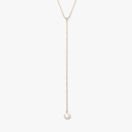 Minimalist gold lariat necklace featuring a single round white pearl drop and a delicate accent stone, centered on a white background.