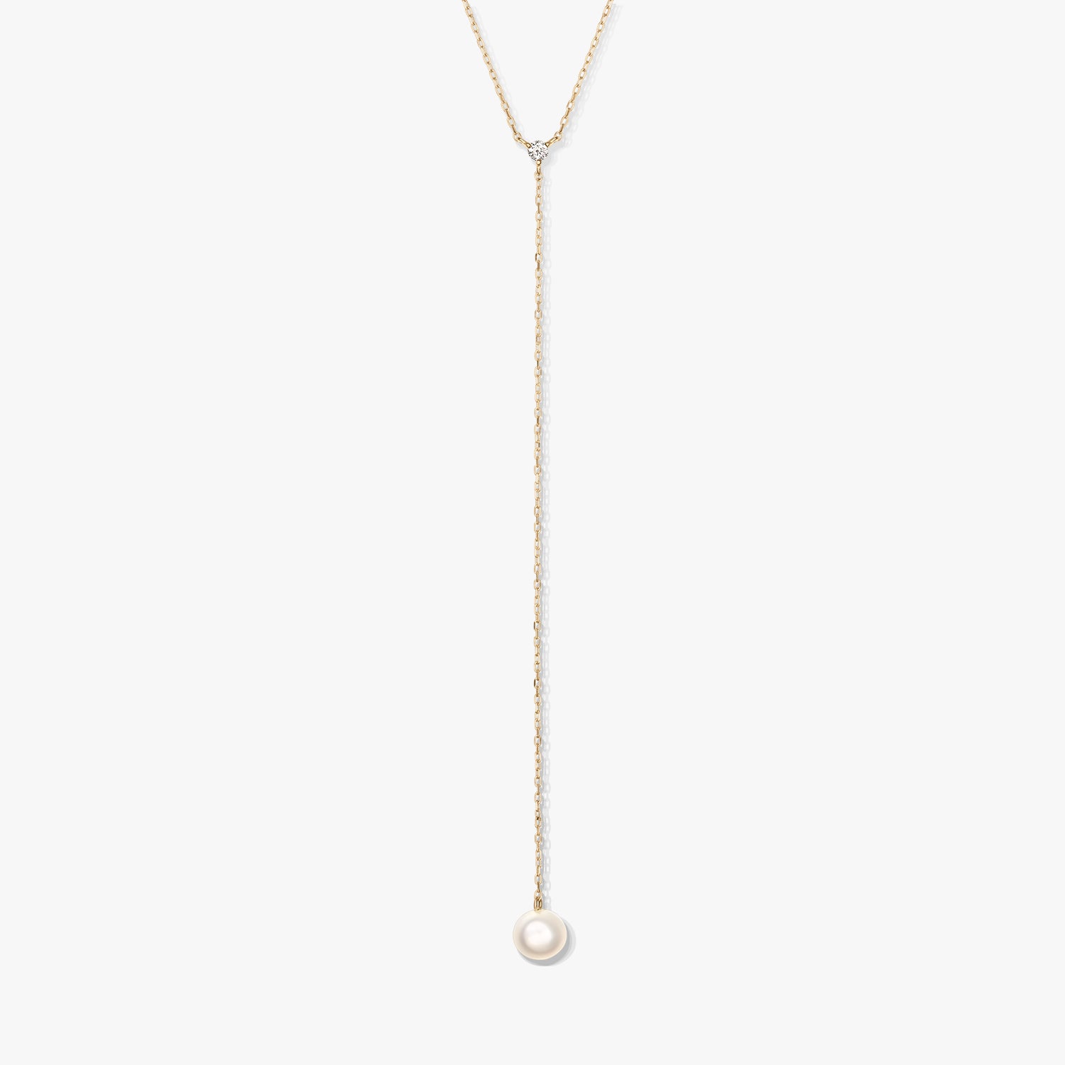 Minimalist gold lariat necklace featuring a single round white pearl drop and a delicate accent stone, centered on a white background.