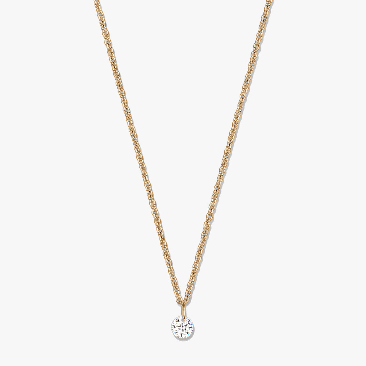 Gold‑tone silver necklace with a single round clear zirconia solitaire pendant on a white background.