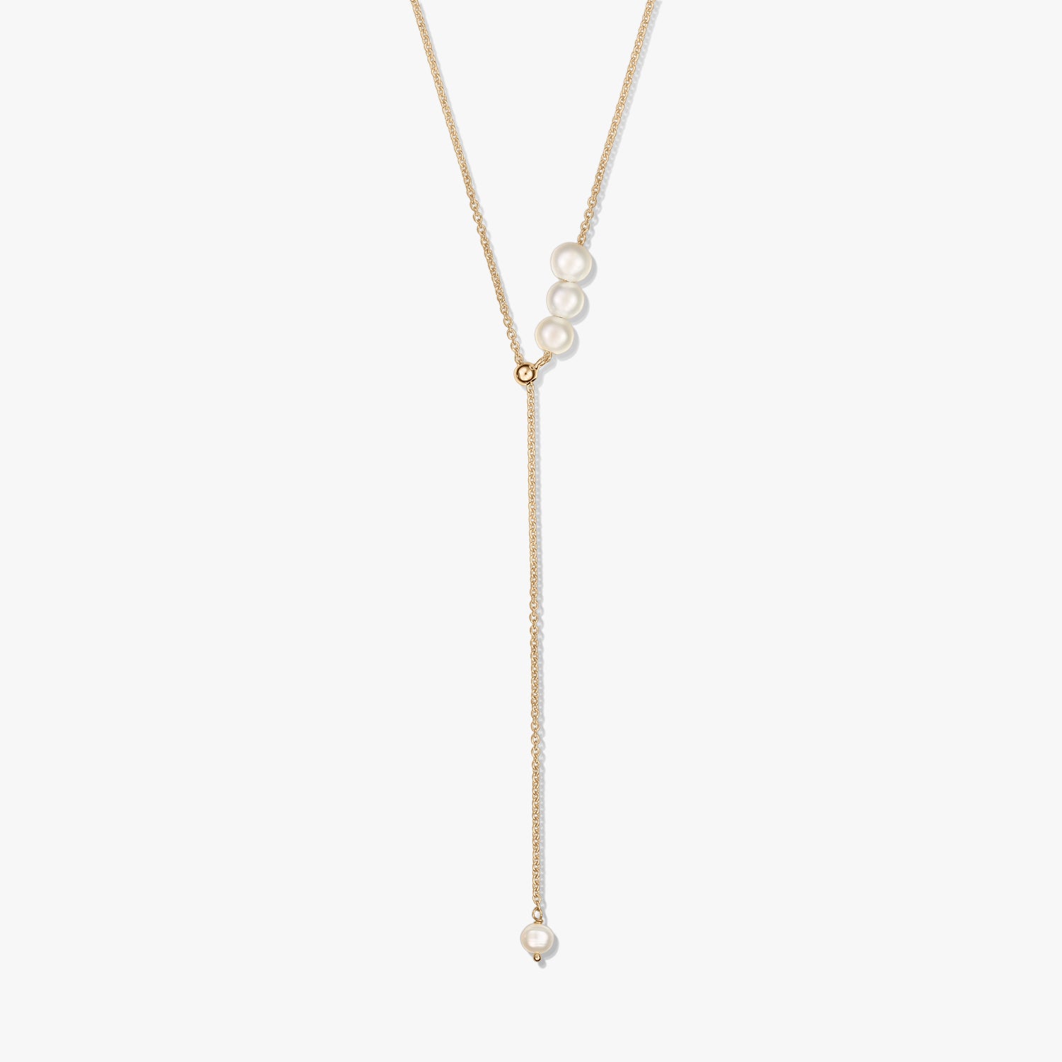 Delicate gold-plated sterling silver lariat necklace featuring a trio of cultured pearls at the slider and a single pearl drop, isolated on white.