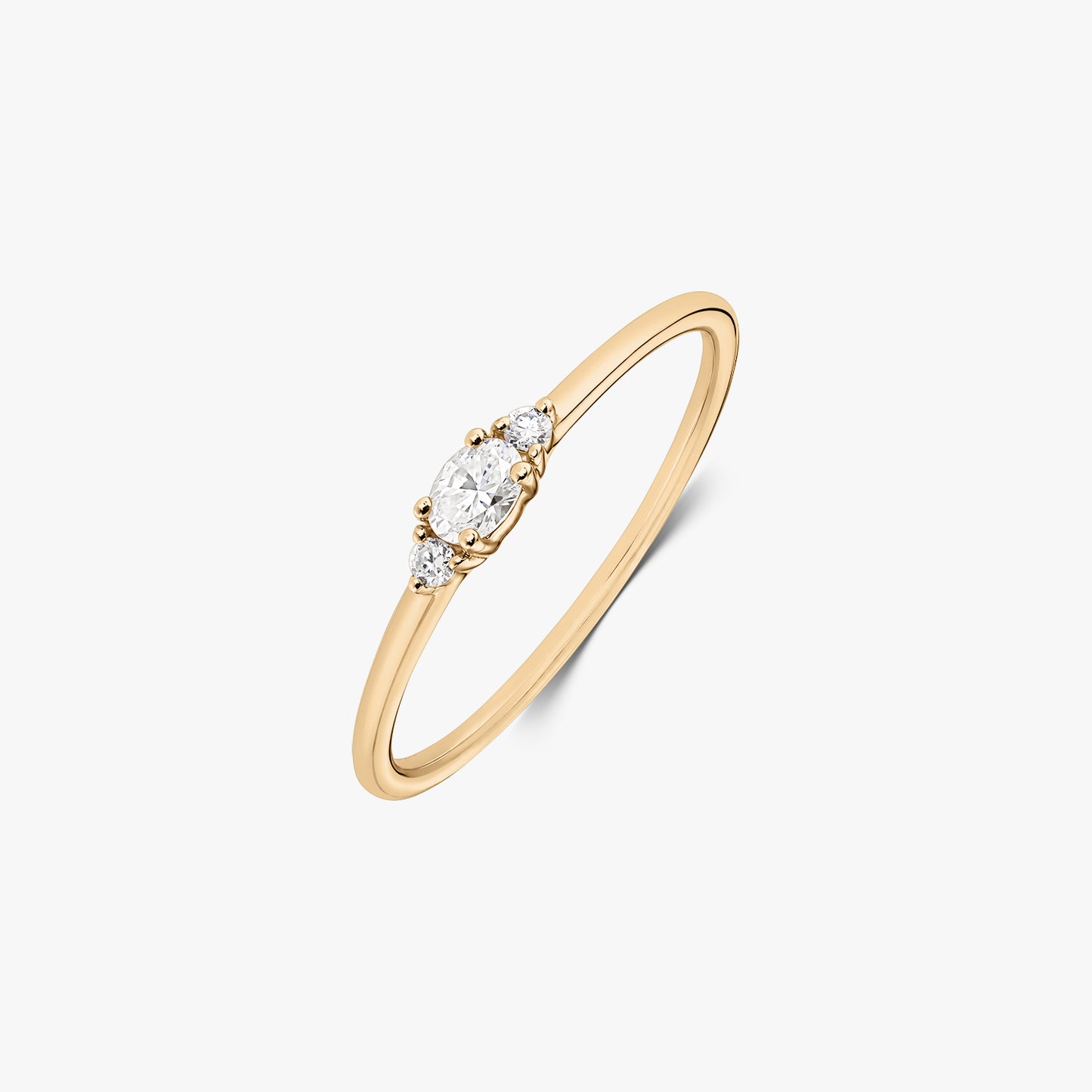 Grace 14K yellow gold ring featuring an oval natural diamond accented by two petite round diamonds on a slim band, elegantly isolated on white.