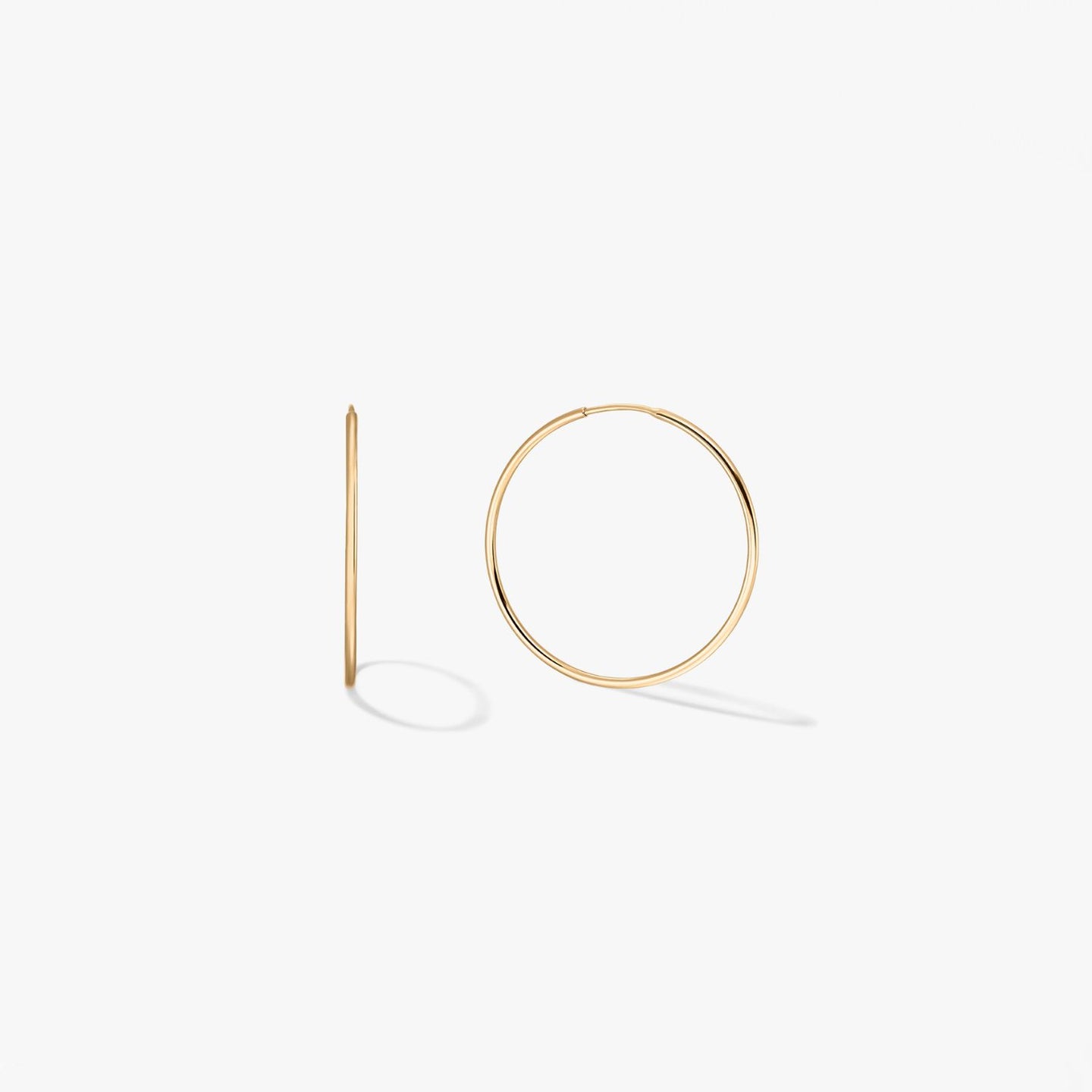 Pair of mini 14k yellow gold hoop earrings on a white background, one shown from the front and one in side profile.