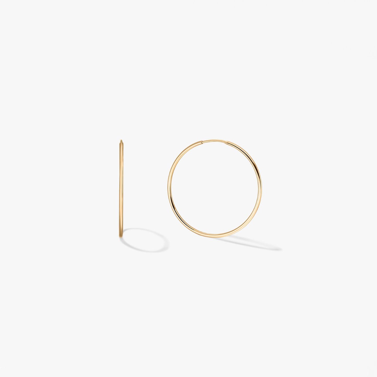 Pair of mini 14k yellow gold hoop earrings on a white background, one shown from the front and one in side profile.