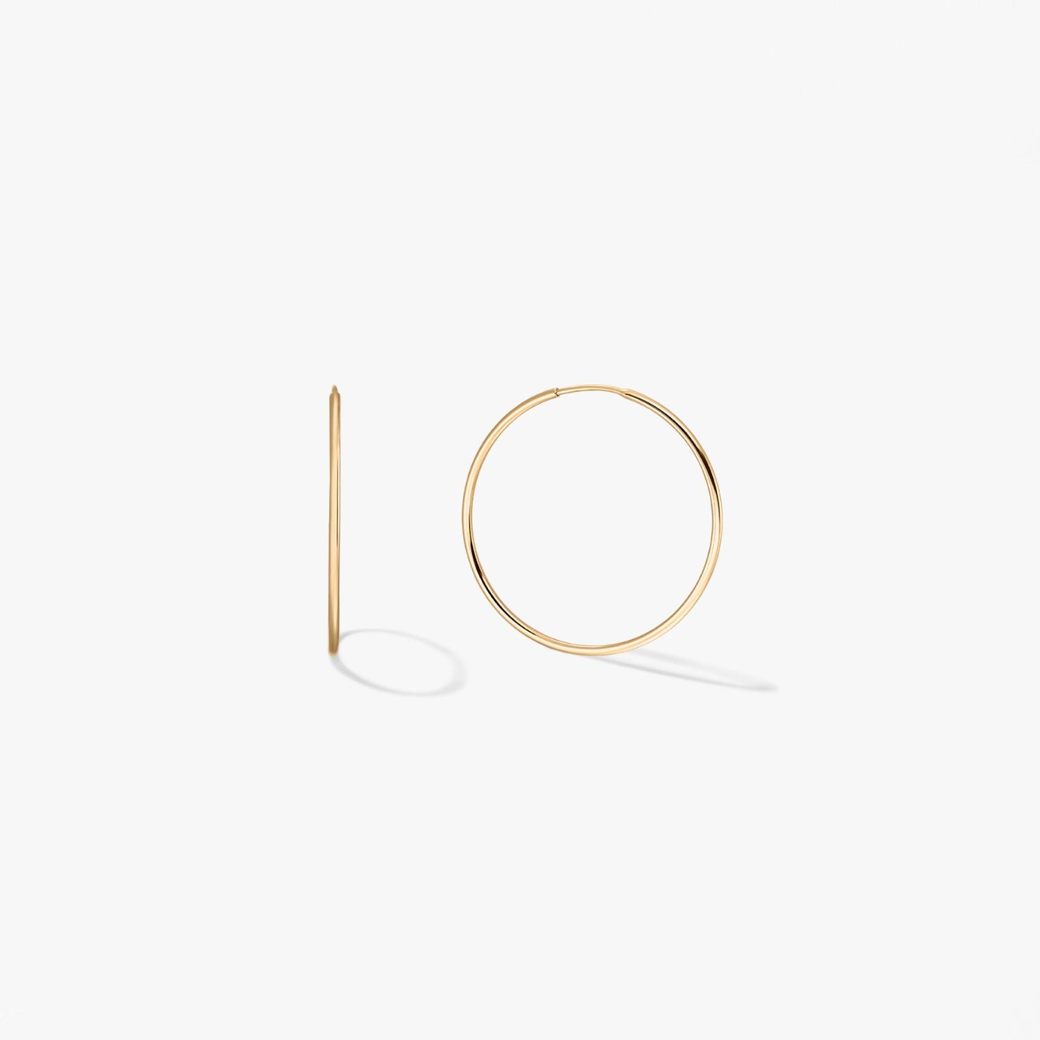 Pair of mini 14k yellow gold hoop earrings on a white background, one shown from the front and one in side profile.