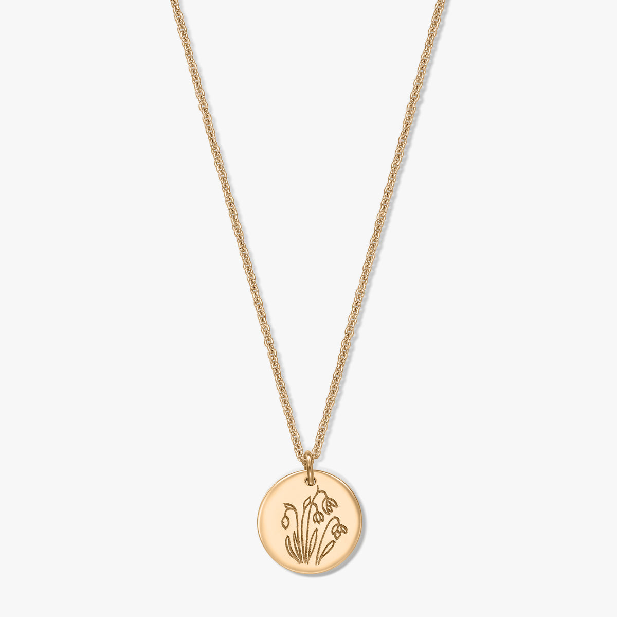Gold‑plated sterling silver necklace with a round disc pendant engraved with the January birth flower snowdrop, shown on a white background.