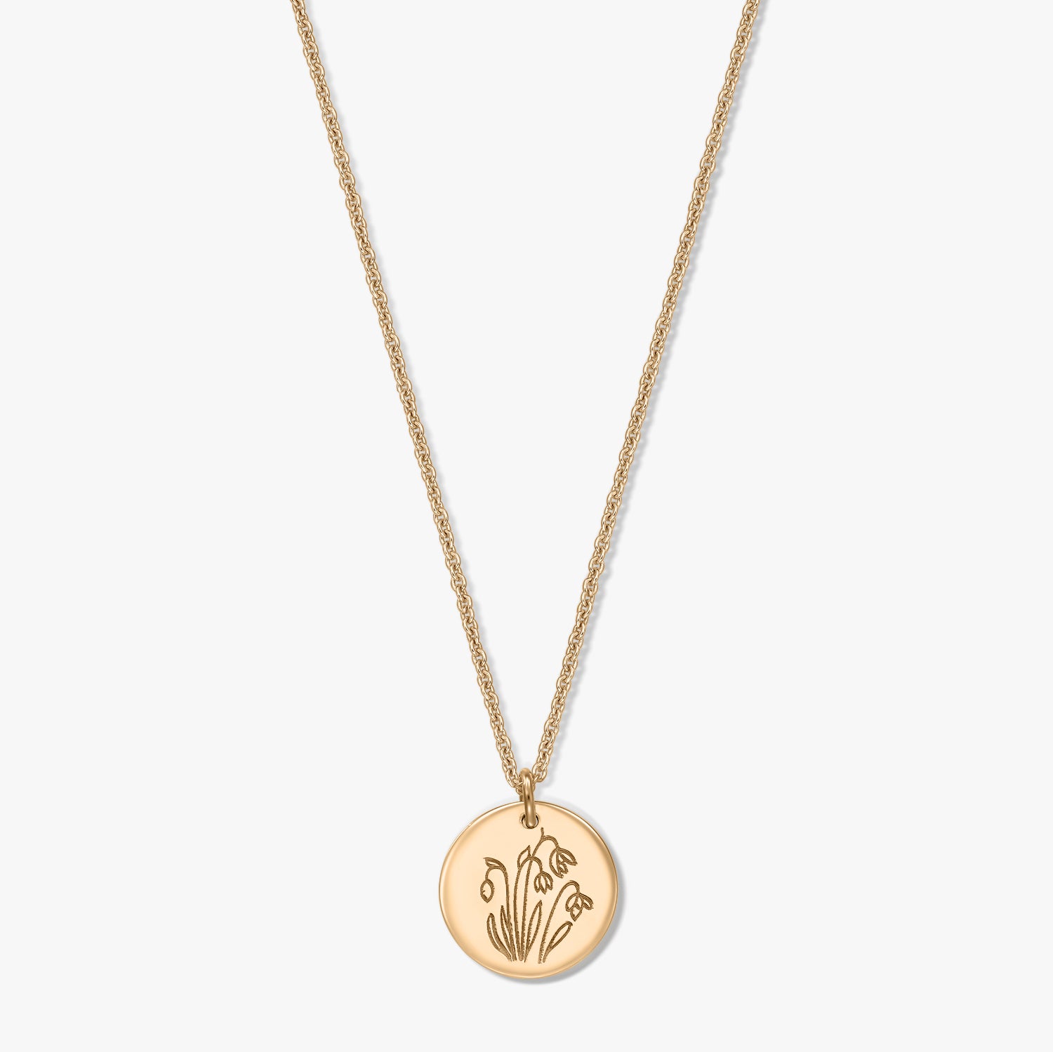 Gold‑plated sterling silver necklace with a round disc pendant engraved with the January birth flower snowdrop, shown on a white background.