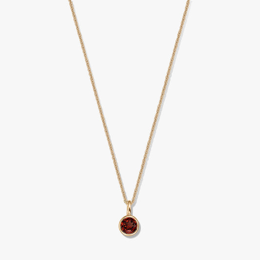 Gold-plated sterling silver birthstone necklace featuring a round bezel-set garnet pendant on a delicate chain, isolated on a white background.