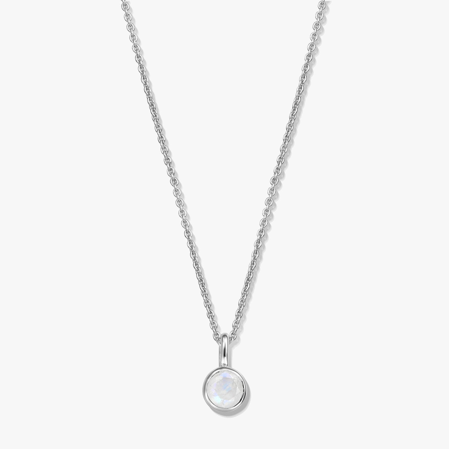 Elegant sterling silver birthstone necklace featuring a round bezel-set moonstone pendant on a fine chain, photographed on a white background.
