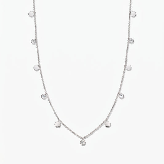 Sterling silver Noora station necklace with alternating polished discs and bezel‑set white topaz stones on a white background.