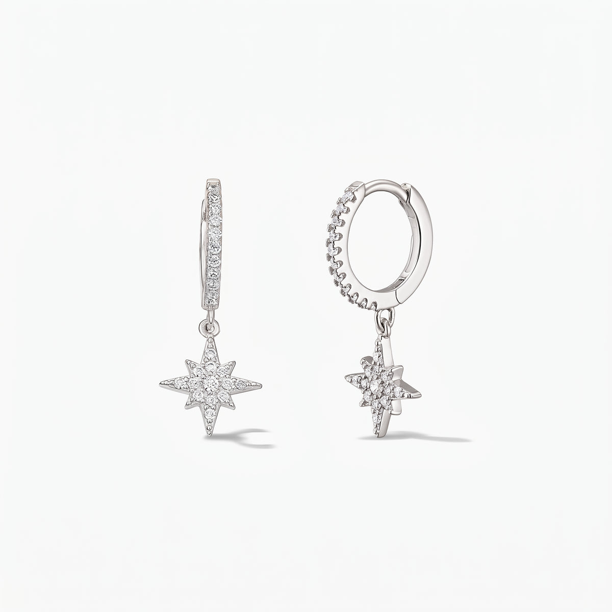 Pair of 925 sterling silver huggie hoop earrings with pavé white zirconia North Star charms on a white background.