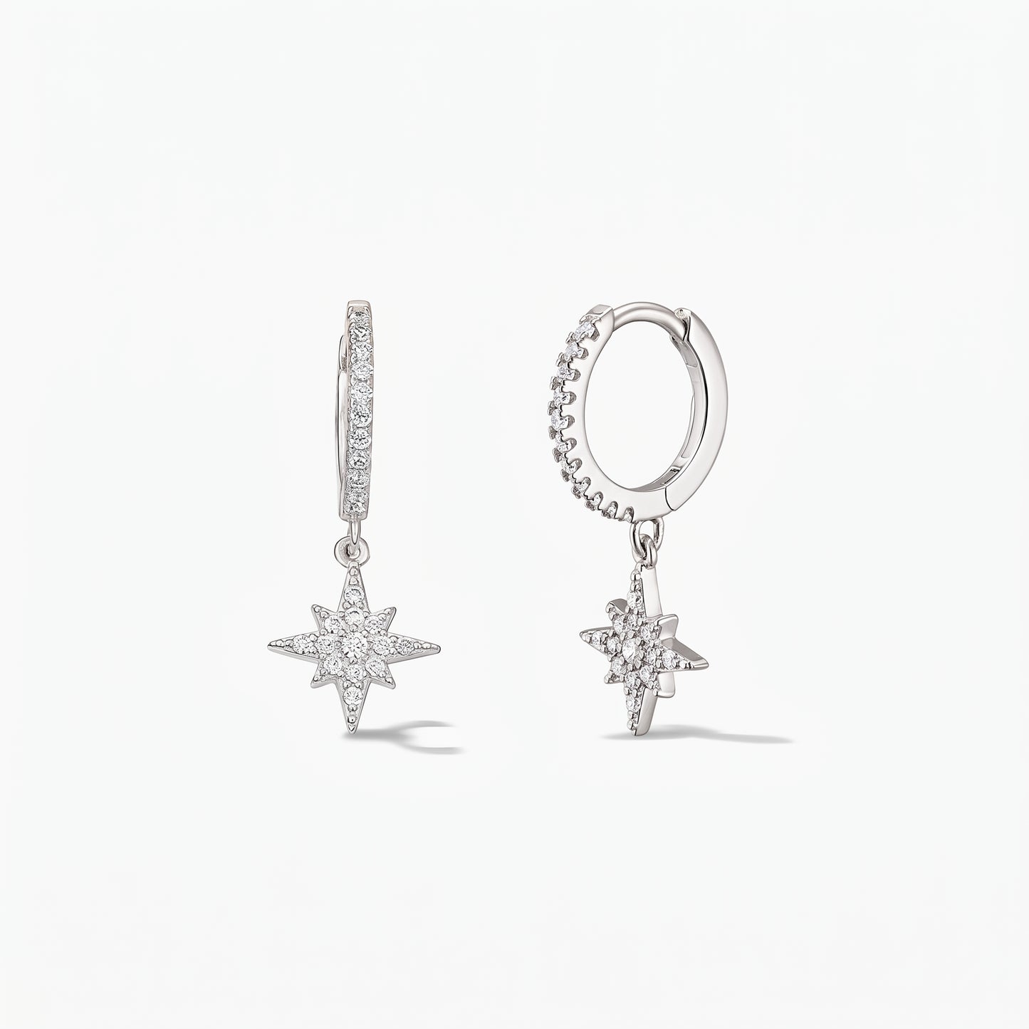 Pair of 925 sterling silver huggie hoop earrings with pavé white zirconia North Star charms on a white background.