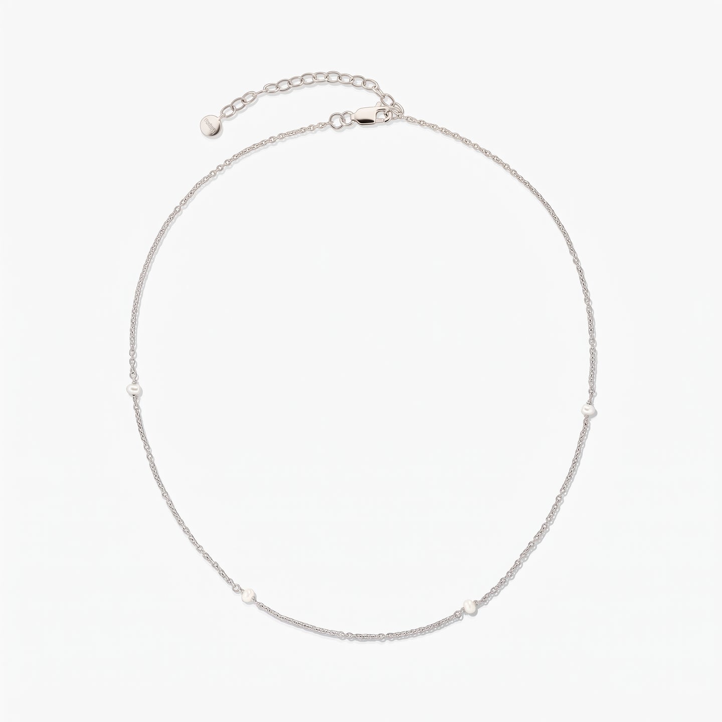 Delicate silver chain necklace with tiny white pearl stations, arranged in a circle on a white background, featuring an adjustable extender and lobster clasp.